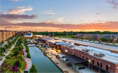 Scenic view of a canal with brick buildings and greenery in Flower Mound, Texas, highlighting the community's charm near small animal veterinary job opportunities.
